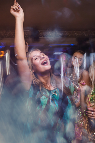 Young woman at a News Year Eve party dancing and smiling and wearing braces on her teeth.