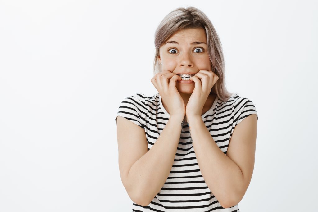Teen girl in striped shirt with metal braces looks scared