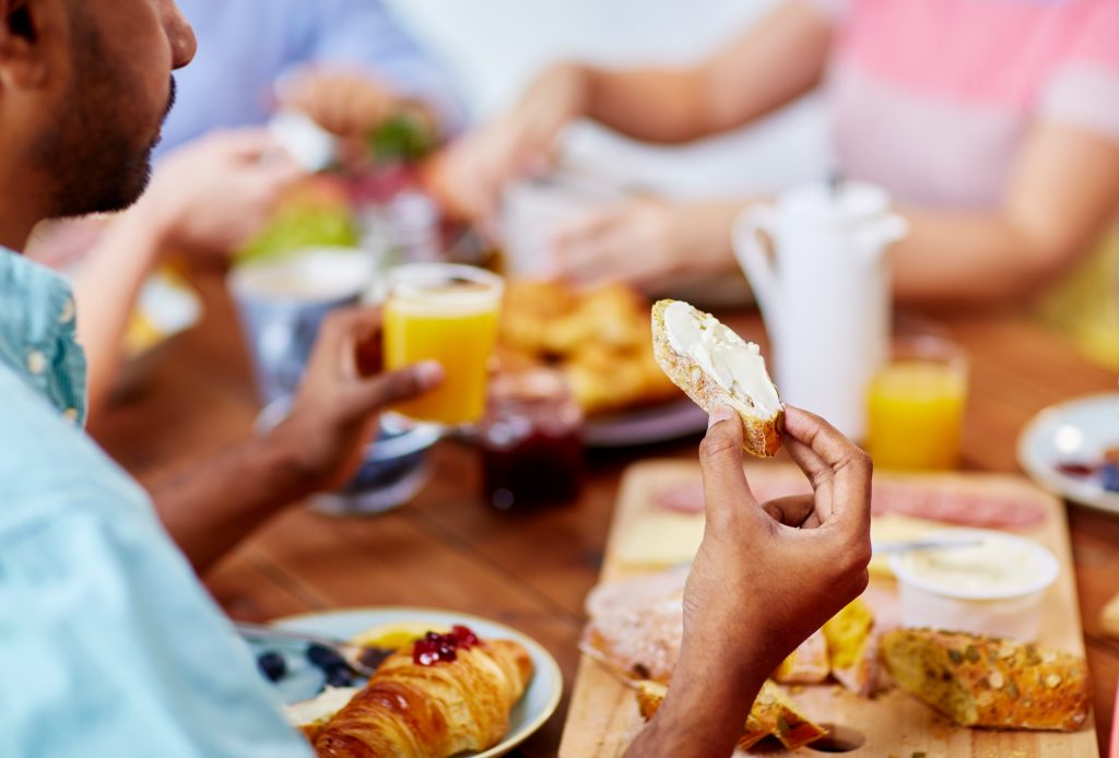 Man eating at a picnic table full of for with friends