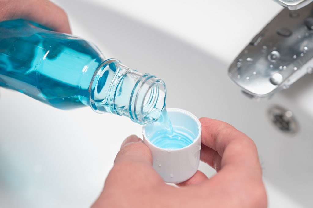 Blue mouthwash being poured into bottle lid.